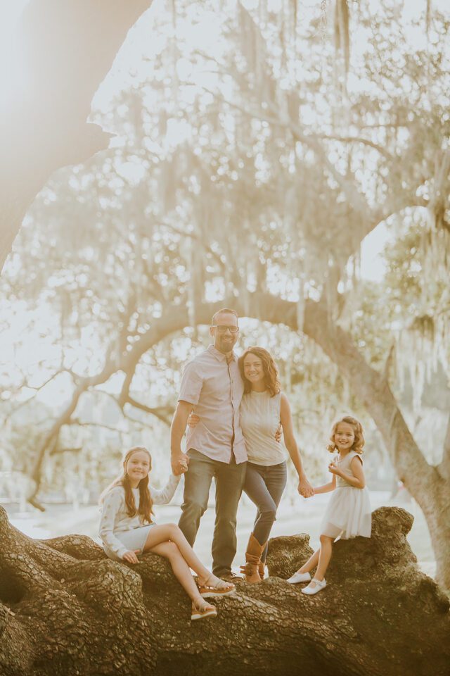 Family under an arcing oak tree branch during golden hour